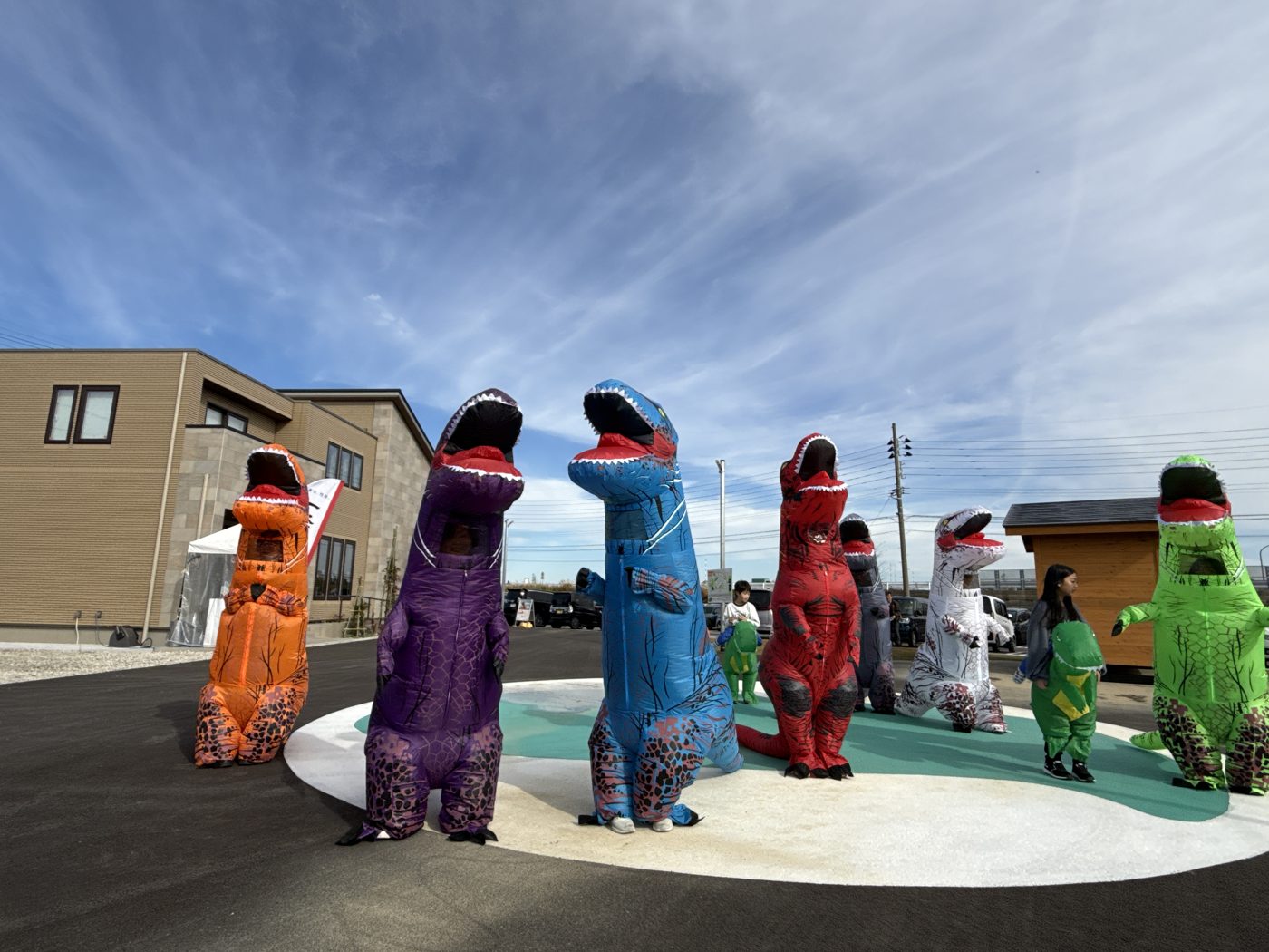 広場に並ぶ、色とりどりの恐竜の着ぐるみ